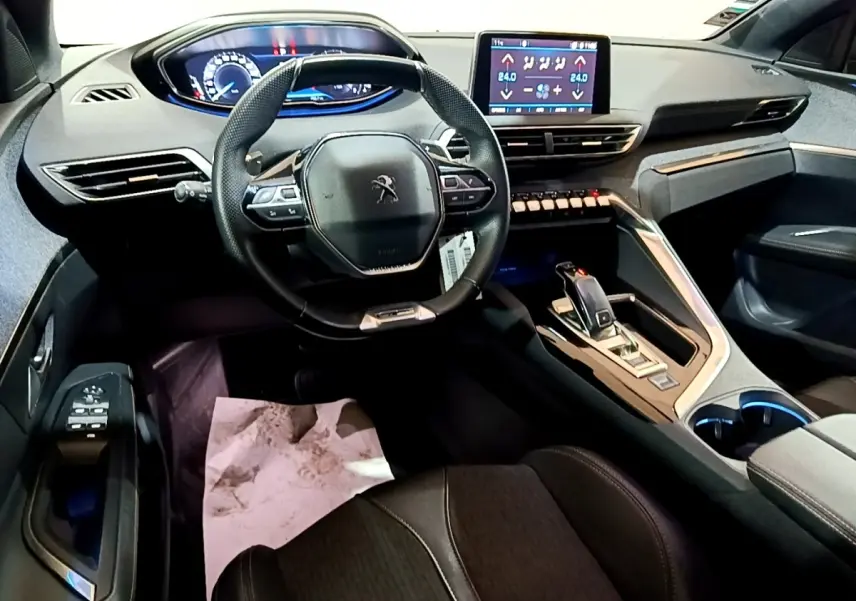 Vue intérieure avant du Peugeot 3008 gris foncé, volant cuir multifonctions et écran tactile central allumé.