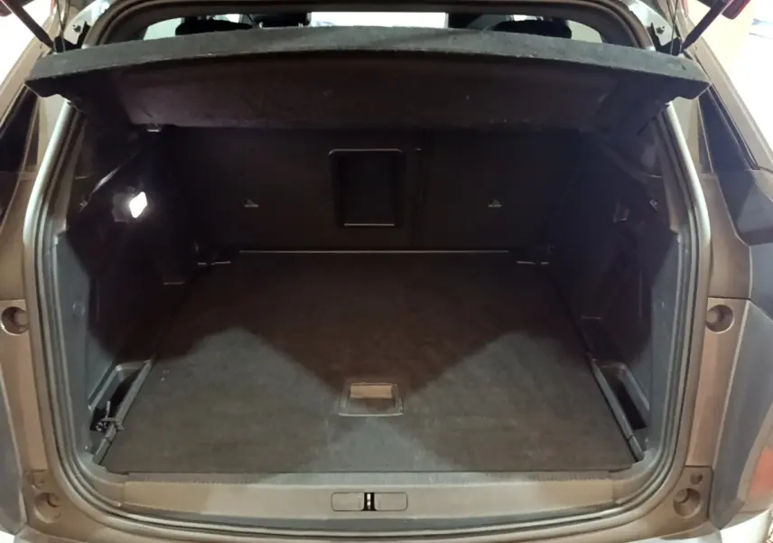 Coffre ouvert vu de l'arrière d'un Peugeot 3008 gris foncé, avec plancher plat et banquette rabattue partiellement.