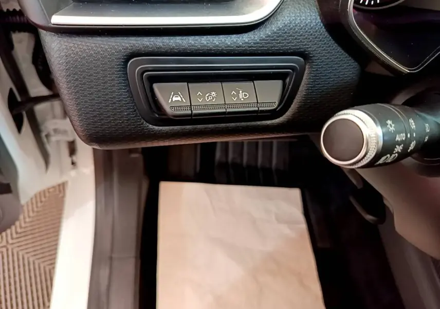 Vue intérieure côté conducteur de la Renault Clio Business Blue dCi 85 blanche, avec commandes d'assistance et éclairage au tableau de bord.