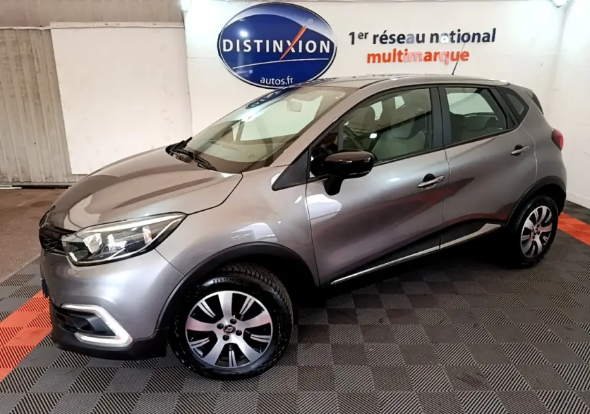 Renault Captur Business gris foncé vu de profil côté gauche dans un showroom avec logo Distinxion en arrière-plan.