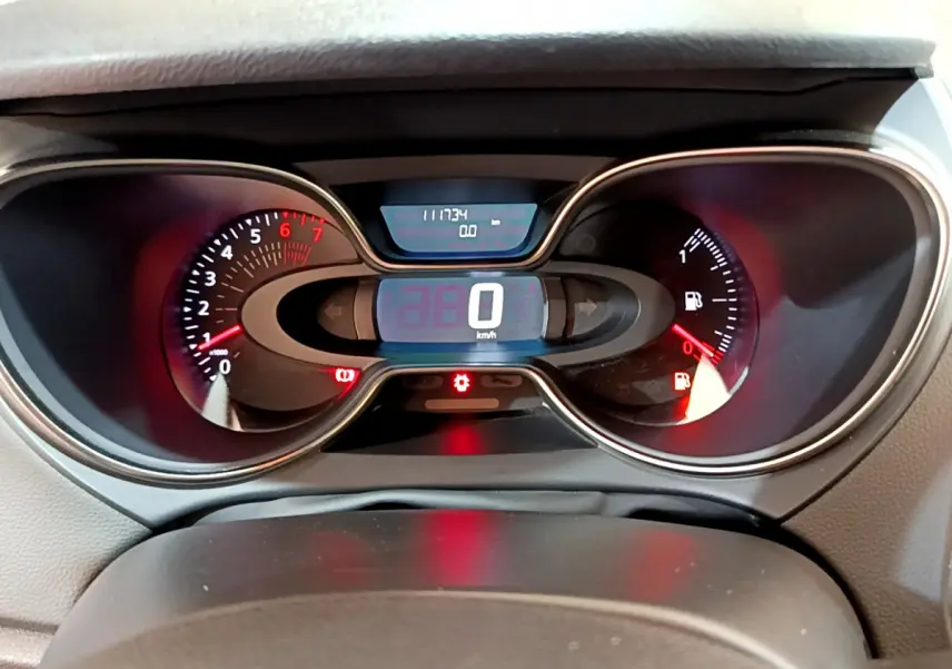 Vue rapprochée du tableau de bord numérique du Renault Captur gris foncé, affichant 0 km/h et jauge essence basse.
