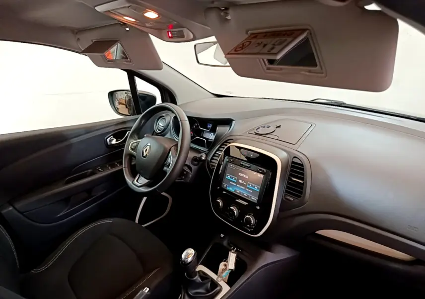 Vue intérieure côté conducteur du Renault Captur Business gris foncé, avec volant cuir, écran tactile 7 pouces et levier de vitesse manuel.