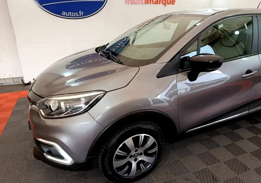 Vue 3/4 avant droit d'un Renault Captur gris foncé avec phares LED et jantes alliage distinctives.