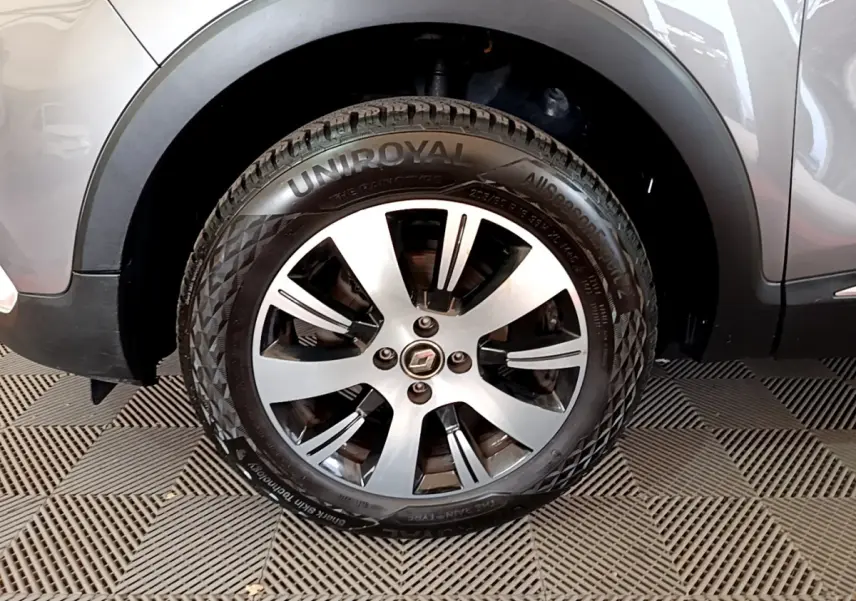 Gros plan sur la roue avant gauche d’un Renault Captur gris foncé, mettant en valeur la jante alliage et le pneu Uniroyal.