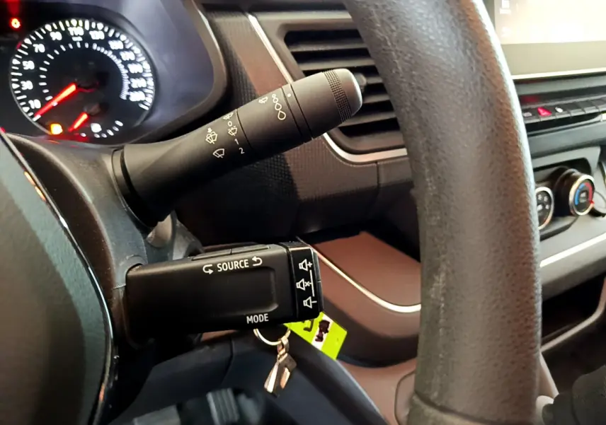 Gros plan sur le volant et les commandes multimédia du tableau de bord du Renault Trafic Fourgon blanc, version 2022.