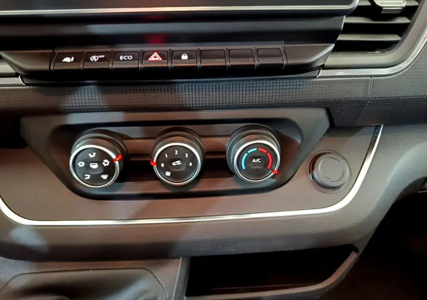 Gros plan sur les commandes de climatisation et boutons de fonction du tableau de bord du Renault Trafic Fourgon blanc 2022.