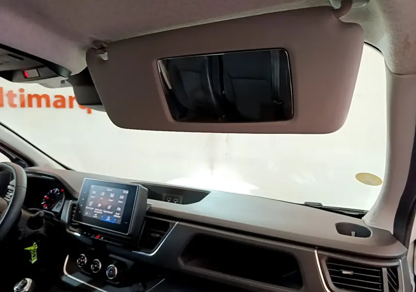 Intérieur du Renault Trafic Fourgon 2022 vu côté passager, tableau de bord moderne avec écran tactile et pare-soleil baissé.