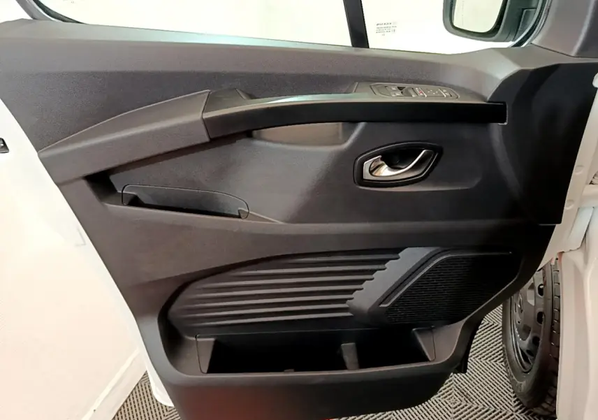 Gros plan sur la porte côté conducteur noire du Renault Trafic Fourgon blanc, avec poignée argentée et haut-parleur intégré.
