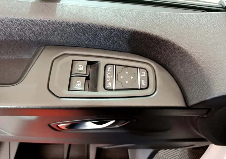 Gros plan sur les commandes électriques des vitres et rétroviseurs côté conducteur du Renault Trafic Fourgon blanc 2022.