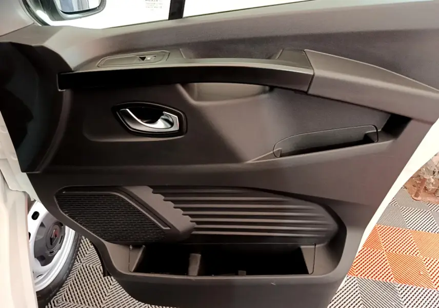 Gros plan sur la porte avant gauche noire du Renault Trafic Fourgon blanc, avec poignée chromée et haut-parleur intégré.