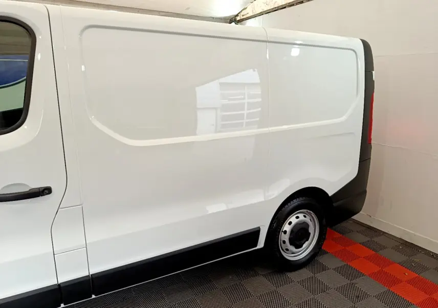 Vue latérale côté droit du fourgon blanc Renault Trafic FG CF L1H1 2T8 Diesel avec jantes acier et porte coulissante.