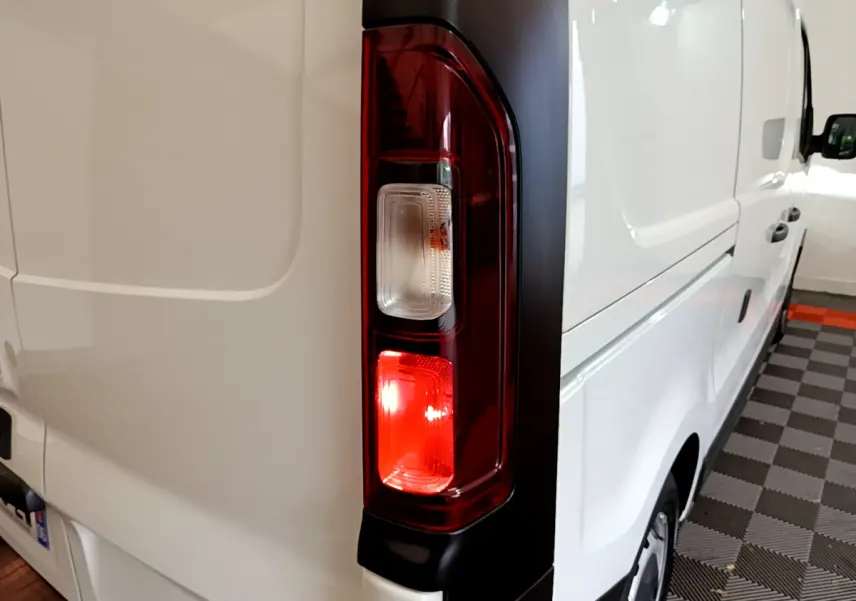 Feu arrière droit allumé sur un Renault Trafic Fourgon blanc vu de trois quarts arrière côté droit.