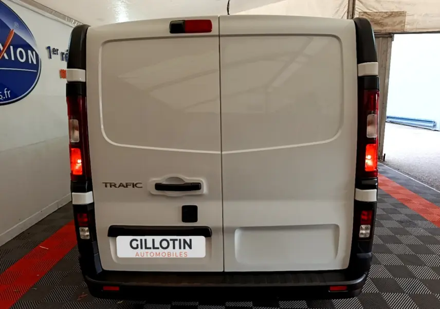 Vue arrière d'un utilitaire Renault Trafic Fourgon blanc avec feux arrière allumés et plaque GILLOTIN Automobiles.