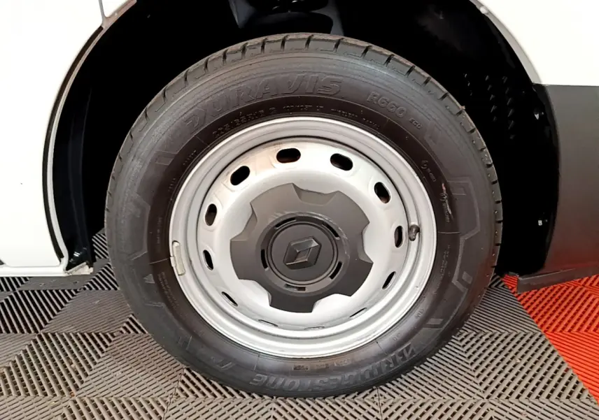 Gros plan sur la roue avant droite blanche du Renault Trafic Fourgon 2022 avec jante acier et logo Renault central.