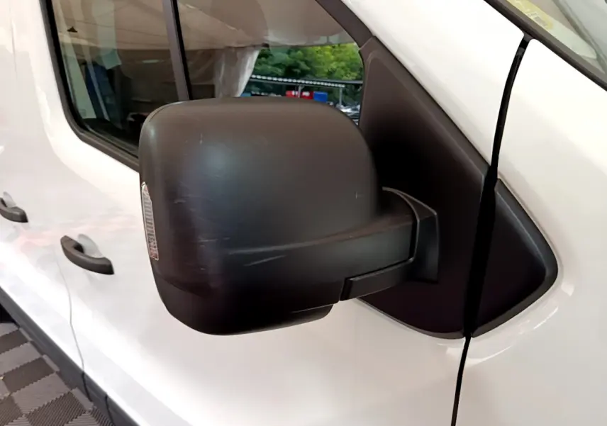 Gros plan sur le rétroviseur noir côté gauche du Renault Trafic Fourgon blanc, vue latérale avant.
