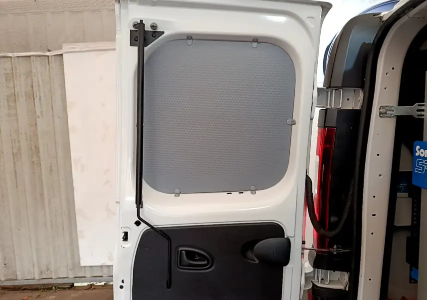 Vue rapprochée de la porte arrière gauche ouverte du Renault Trafic Fourgon blanc, montrant la cloison pleine intérieure.