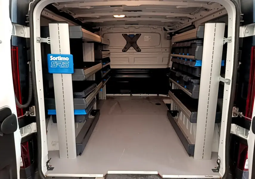 Vue arrière intérieure du fourgon blanc Renault Trafic FG CF L1H1 2022 avec étagères de rangement Sortimo SR5.