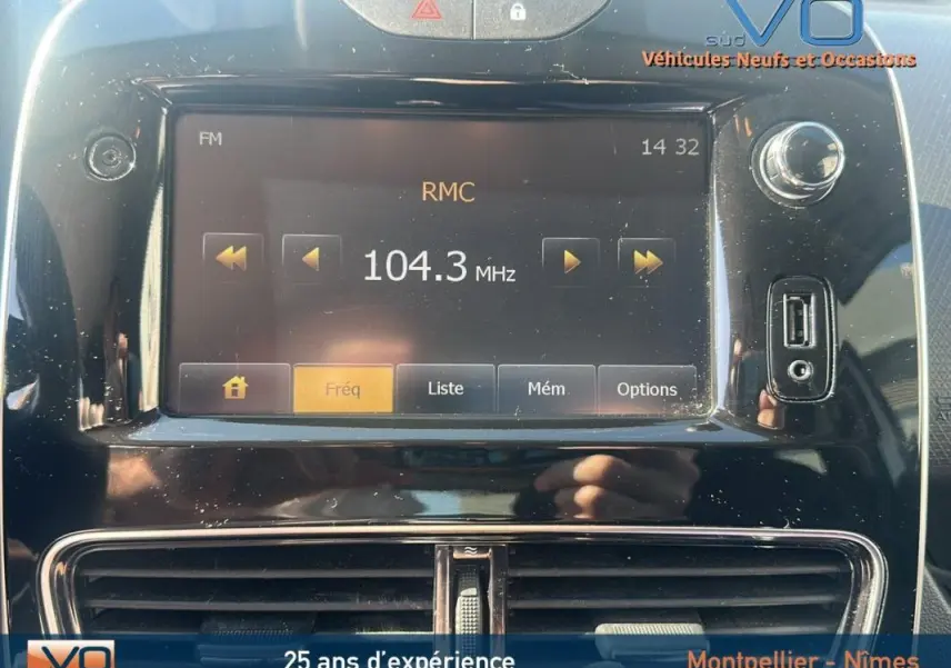 Vue rapprochée de l'écran multimédia noir de la Renault Clio IV Estate Business blanc affichant la radio FM sur 104.3 MHz