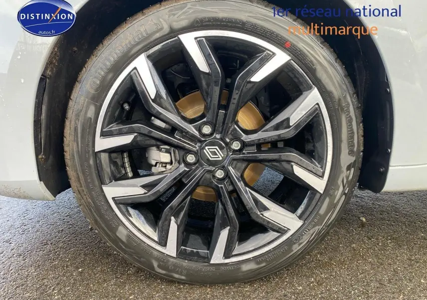 Gros plan sur la jante alu noire et argentée de la Renault Clio V gris rafale, avec logo Renault central.