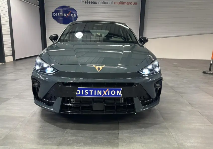 Vue frontale d'une CUPRA Leon bleu Fjord avec phares LED allumés et logo CUPRA cuivré sur le capot.