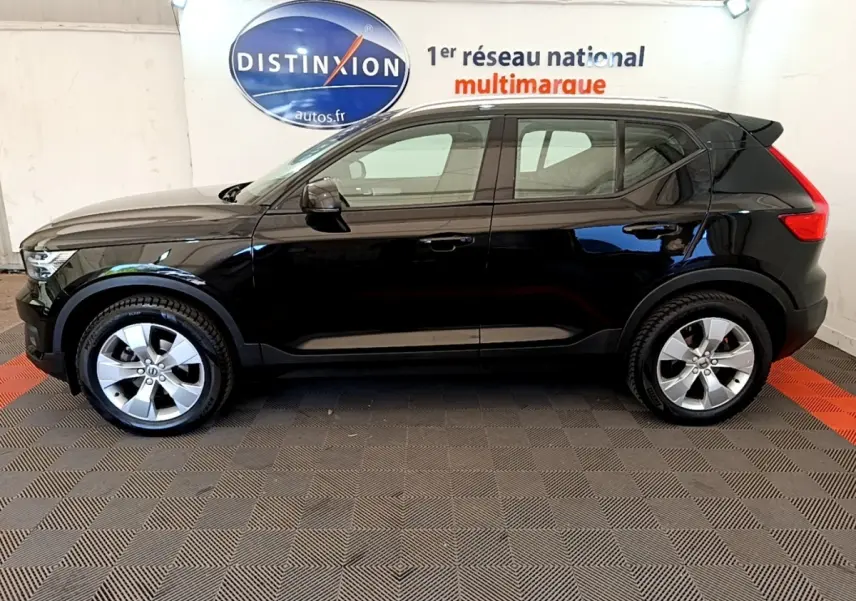 Vue de profil côté gauche d'un Volvo XC40 T2 noir 2020 dans un showroom avec sol à damier.