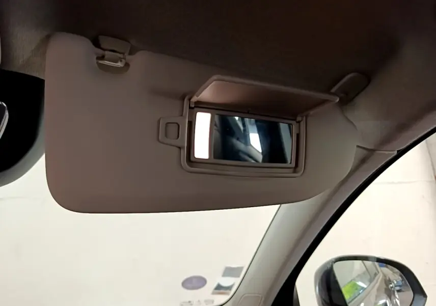 Miroir de courtoisie ouvert sur pare-soleil beige côté conducteur dans un Volvo XC40 noir, vue intérieure avant gauche.