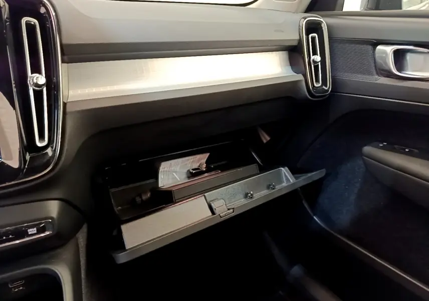 Intérieur de la Volvo XC40 T2 2020, vue côté passager sur la boîte à gants ouverte et tableau de bord clair.