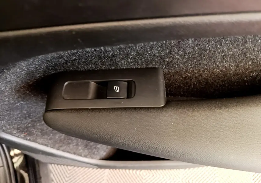 Gros plan sur le bouton de commande de la vitre électrique côté porte intérieure d’un Volvo XC40 noir.