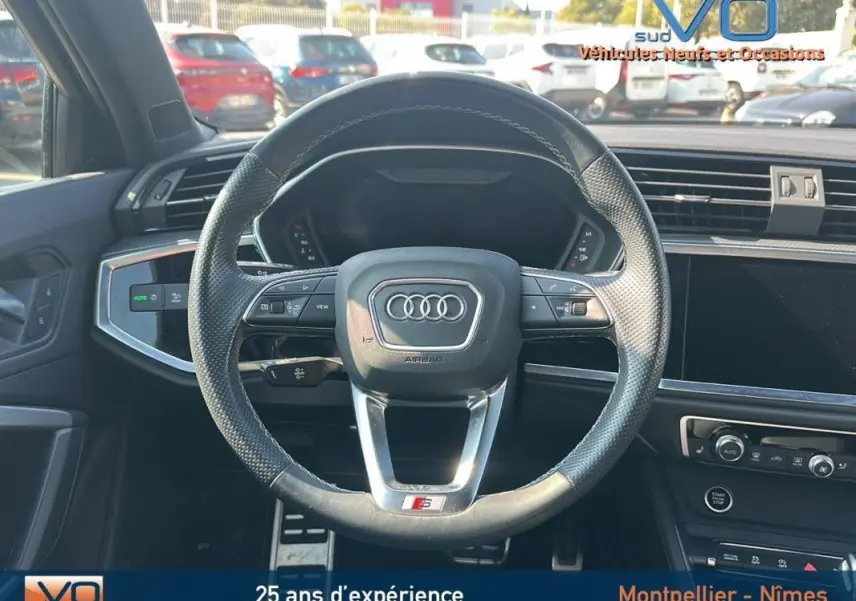 Vue frontale du volant cuir perforé noir avec logo Audi et badge S line dans l'habitacle du Q3 Sportback 2020 noir.