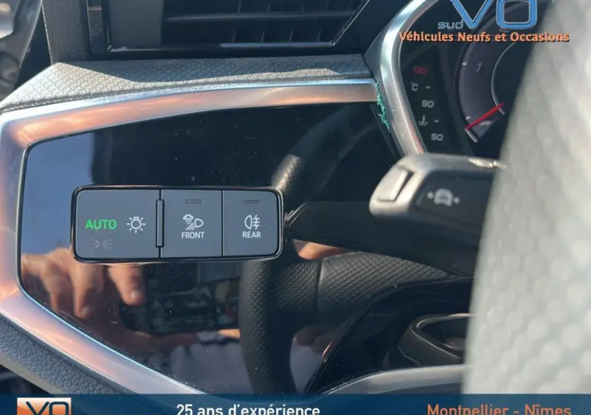 Gros plan sur les commandes d'éclairage automatiques à gauche du volant d'un Audi Q3 Sportback noir S line 2020.