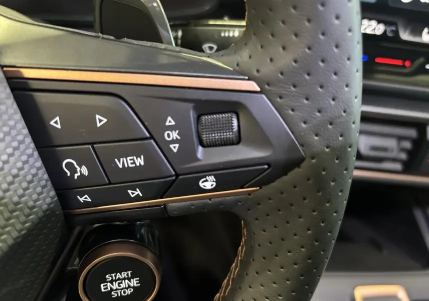 Gros plan sur le volant perforé noir avec surpiqûres cuivrées et boutons multifonctions du CUPRA Leon 2026 gris Magnetic.