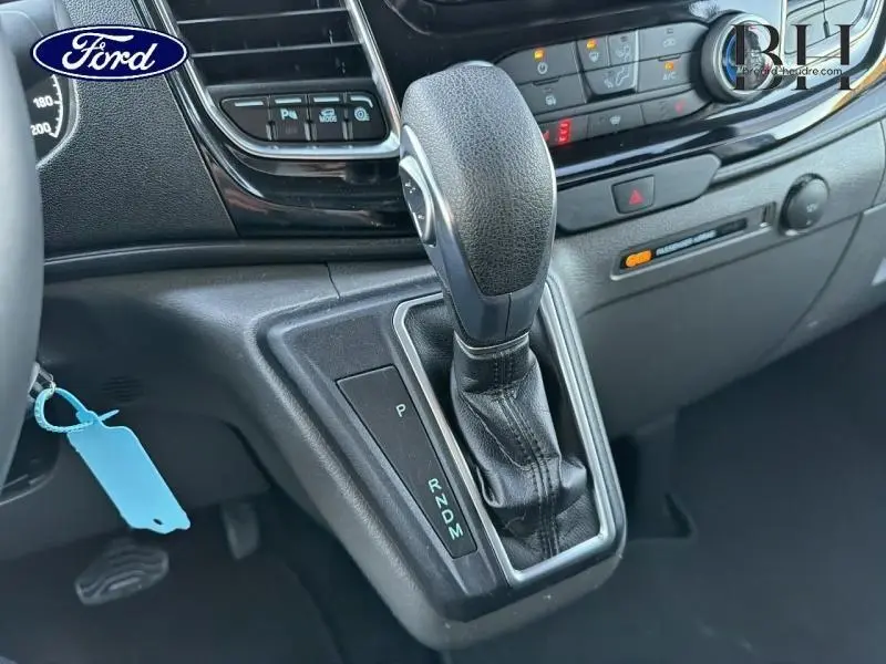 Gros plan sur le levier de vitesses automatique en cuir noir du Ford Transit Custom Fourgon 2023, tableau de bord en arrière-plan.