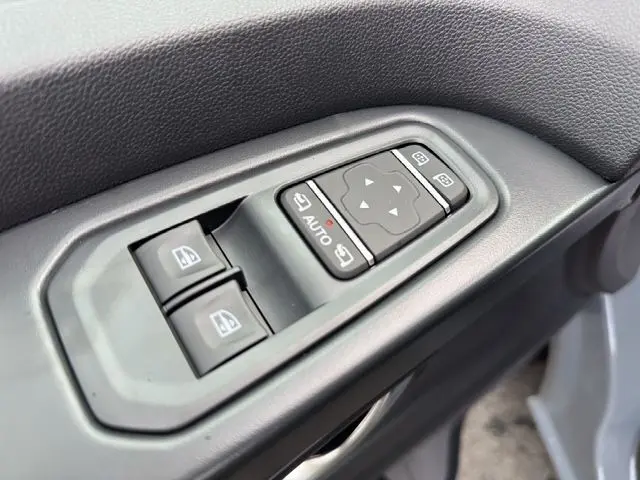 Gros plan sur les commandes de lève-vitres et réglage des rétroviseurs du côté conducteur du Renault Trafic Fourgon Gris Urbain.