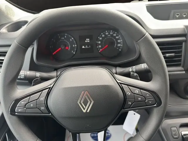 Vue rapprochée du volant gris du Renault Trafic Fourgon 2025, avec commandes intégrées et tableau de bord visible.
