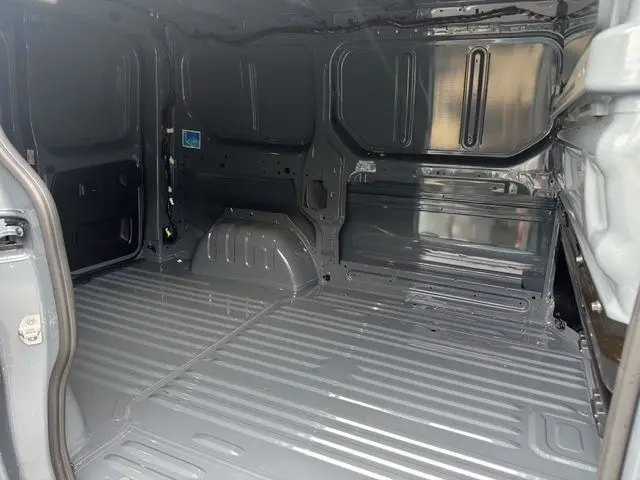 Vue intérieure de la zone de chargement du Renault Trafic Fourgon gris urbain, montrant la cloison et le plancher métallique.