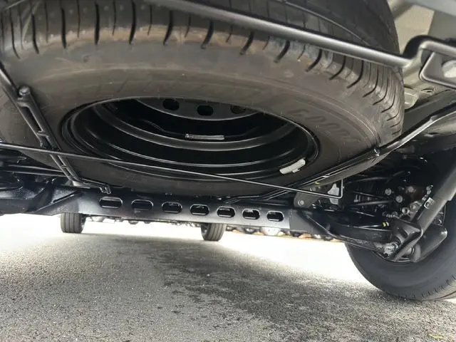 Vue en gros plan sous le Renault Trafic Fourgon gris urbain, montrant la roue de secours fixée sous le châssis.