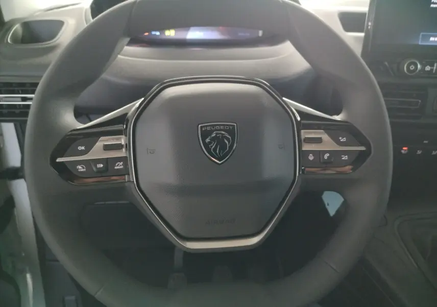 Vue rapprochée du volant multifonction noir du Peugeot Partner FGN 2025 avec commandes intégrées et logo central.
