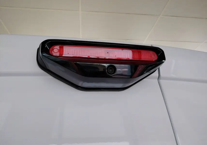Gros plan sur le feu stop arrière rouge avec caméra intégrée du Peugeot Partner FGN blanc Icy, vue arrière haute.