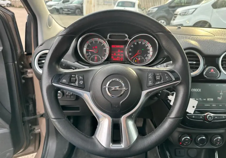 Vue intérieure centrée sur le volant cuir multifonctions d'une Opel Adam marron avec tableau de bord et écran tactile.