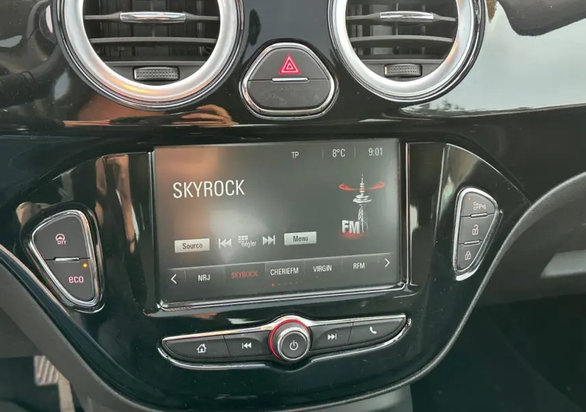 Vue rapprochée de la console centrale noire brillante de l'Opel Adam avec écran tactile affichant la radio Skyrock.