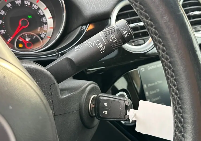 Gros plan sur le volant cuir et le contacteur avec clé insérée dans l'Opel Adam 2016, intérieur noir brillant.