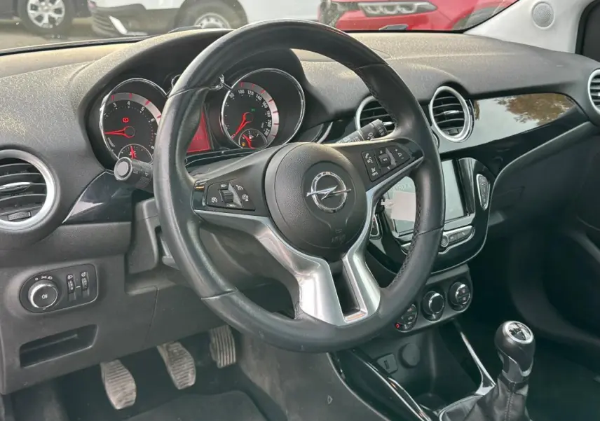 Vue intérieure du tableau de bord de l'Opel Adam 2016, volant cuir multifonctions et levier de vitesse manuelle visibles.