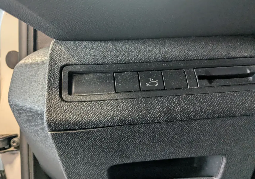 Gros plan sur le bouton d'ouverture du coffre intérieur noir du Peugeot 3008 blanc toit noir, version 2018.