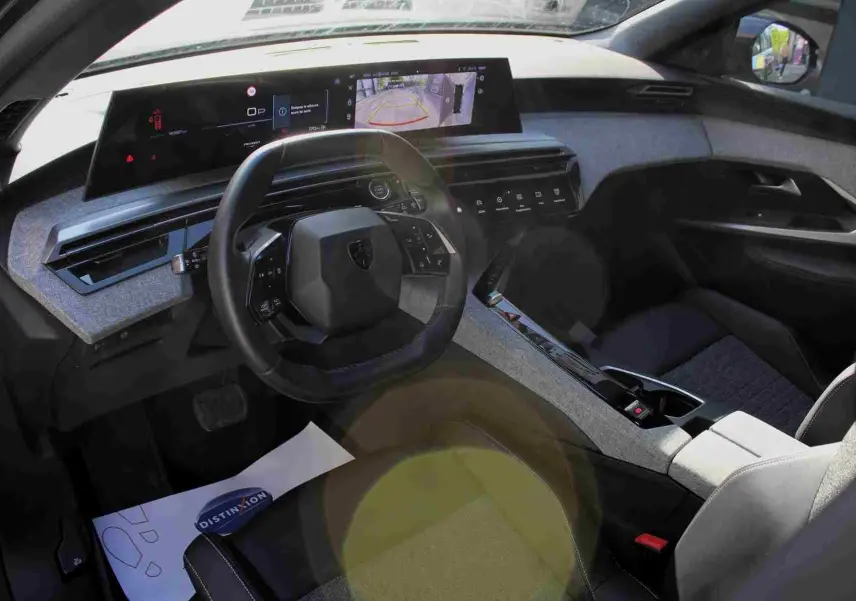 Vue intérieure côté conducteur du Peugeot 5008 gris titane, mettant en valeur le tableau de bord numérique et le volant compact.