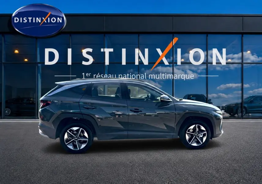Vue latérale côté gauche d'un Hyundai Tucson vert foncé 2026 garé devant une vitrine avec logo Distinxion.