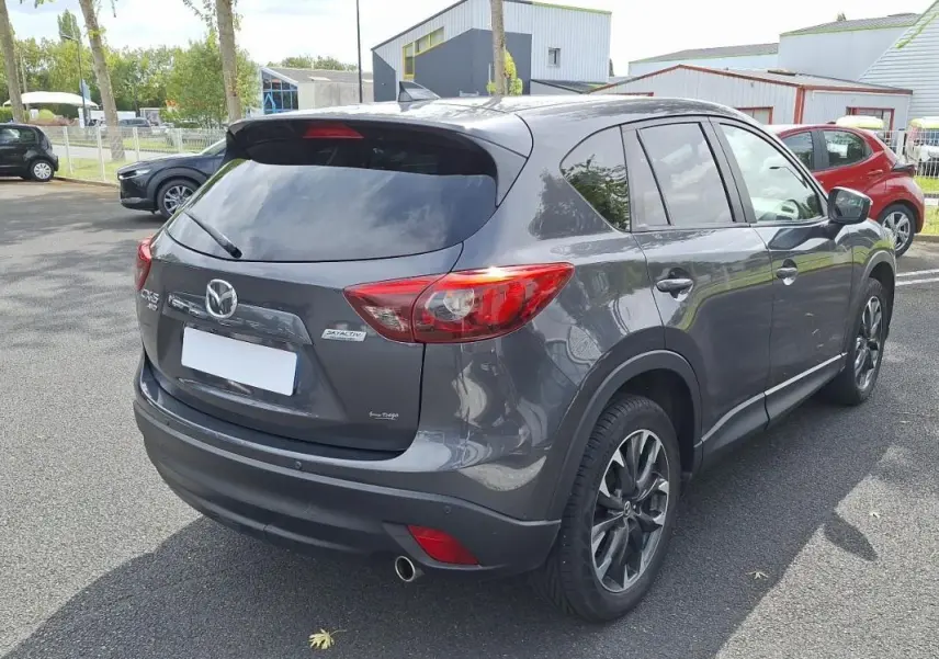 Vue 3/4 arrière droite d'un Mazda CX-5 gris métallisé avec jantes alliage et vitres surteintées.