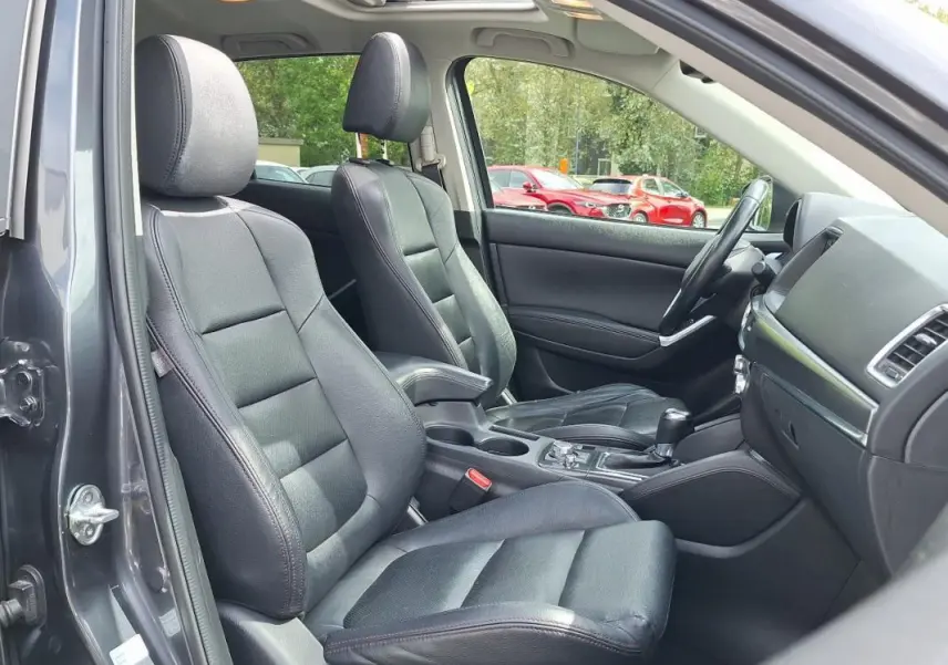 Intérieur noir cuir du Mazda CX-5 2015 vu côté conducteur avec toit ouvrant électrique et tableau de bord moderne.