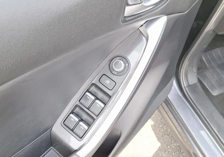 Gros plan sur la porte avant gauche gris clair du Mazda CX-5 avec commandes électriques des vitres et rétroviseurs.