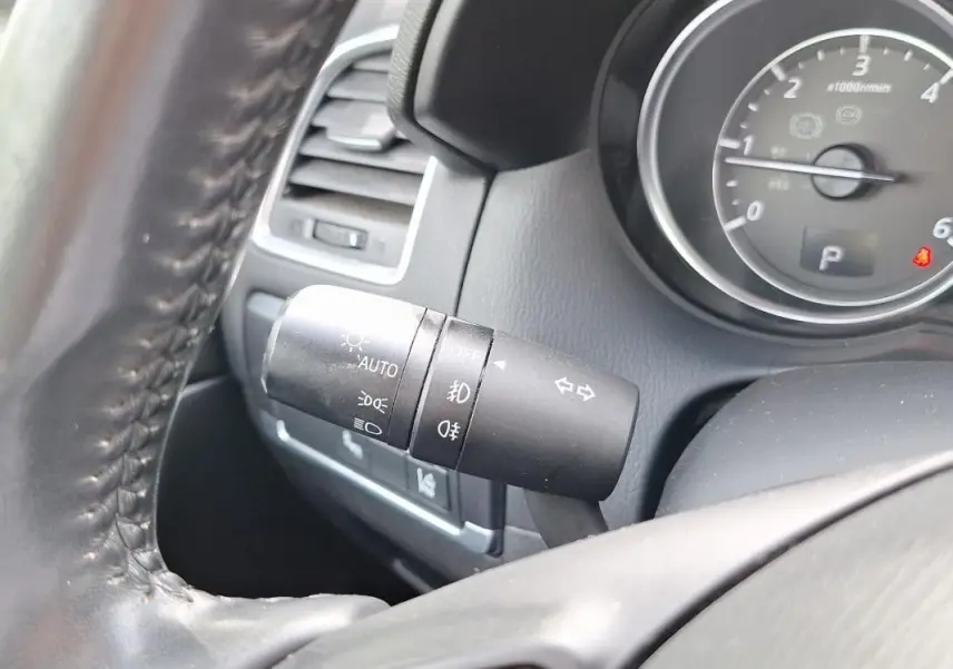 Gros plan sur la manette des feux et clignotants à gauche du volant en cuir du Mazda CX-5 gris 2015.