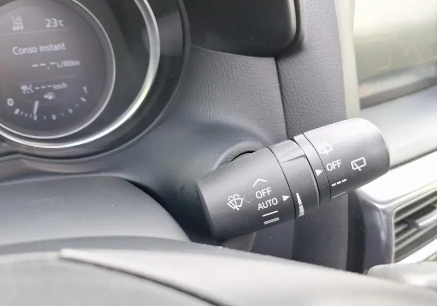 Gros plan sur la commande d'essuie-glace à droite du volant du Mazda CX-5 gris, tableau de bord en arrière-plan.